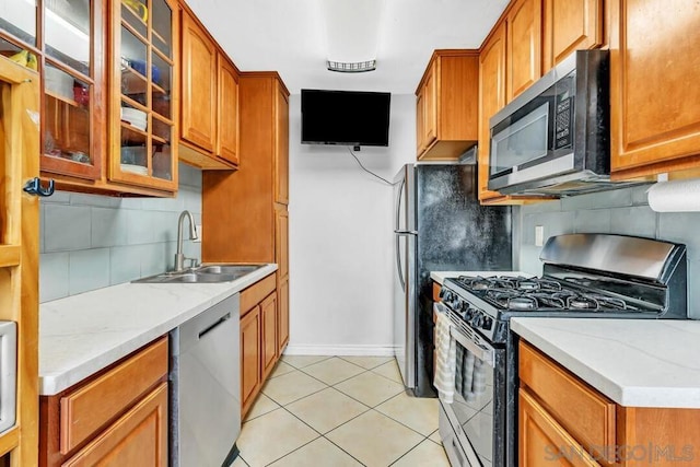 kitchen with sink, light tile patterned flooring, light stone countertops, and appliances with stainless steel finishes