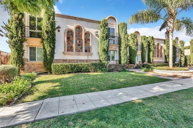 mediterranean / spanish house with a front lawn and a balcony