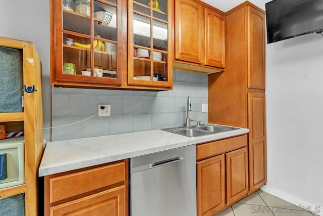 kitchen with light tile patterned flooring, sink, stainless steel dishwasher, light stone countertops, and backsplash