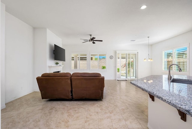 living room featuring ceiling fan with notable chandelier and sink