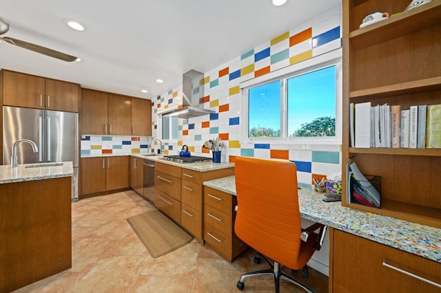 kitchen featuring ceiling fan, backsplash, stainless steel appliances, light stone countertops, and wall chimney exhaust hood