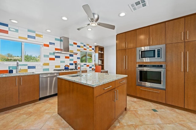 kitchen featuring sink, a kitchen island with sink, stainless steel appliances, light stone counters, and extractor fan