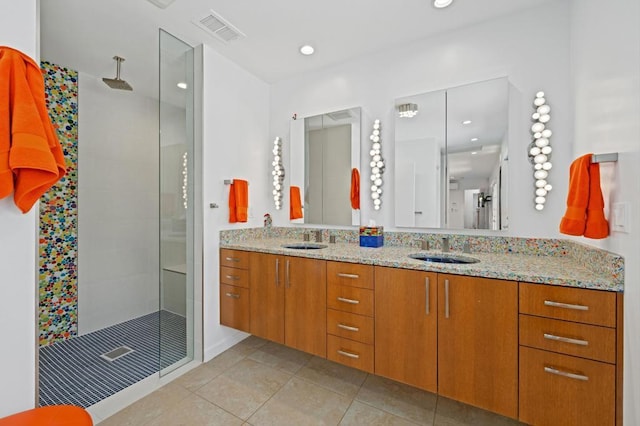 bathroom with a tile shower, vanity, and tile patterned flooring