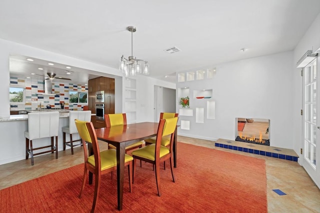 tiled dining space featuring a tile fireplace and ceiling fan