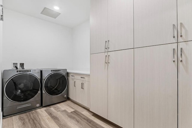 laundry area with independent washer and dryer, light hardwood / wood-style flooring, and cabinets