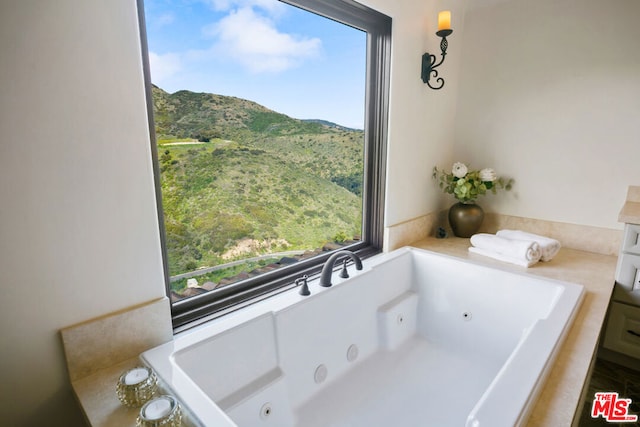 bathroom featuring a mountain view, a wealth of natural light, and a bathtub