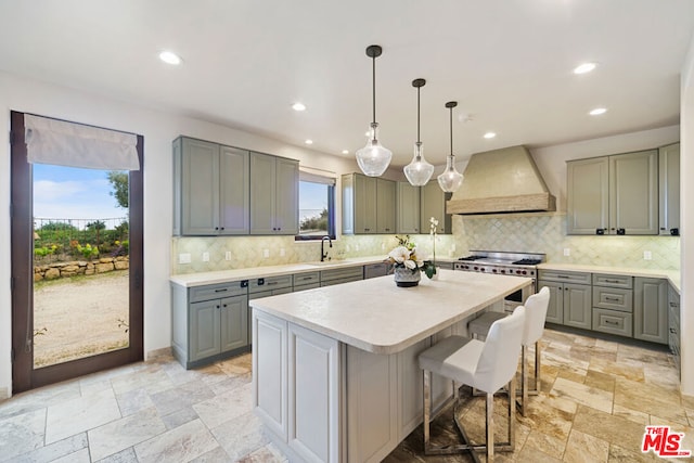 kitchen featuring gray cabinets, premium range hood, pendant lighting, high end range, and a center island