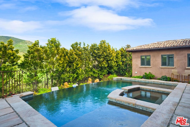 view of pool with an in ground hot tub and a mountain view