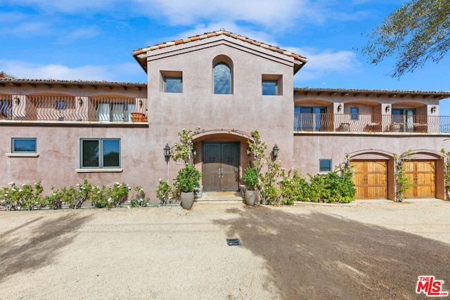 mediterranean / spanish-style house featuring a garage and a balcony