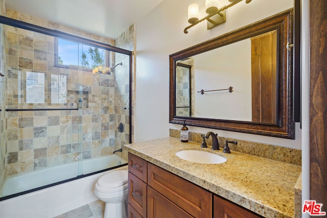 full bathroom featuring vanity, combined bath / shower with glass door, and toilet