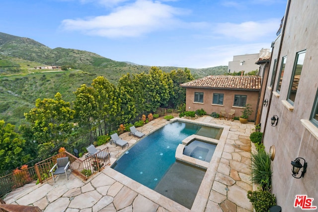 view of swimming pool featuring a mountain view, a patio, and an in ground hot tub