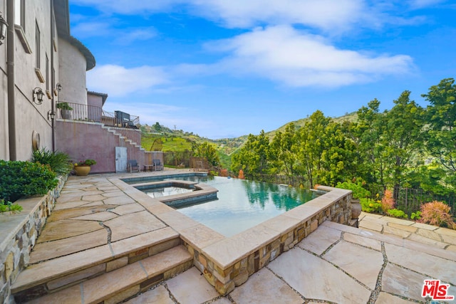 view of swimming pool featuring an in ground hot tub, a mountain view, and a patio area