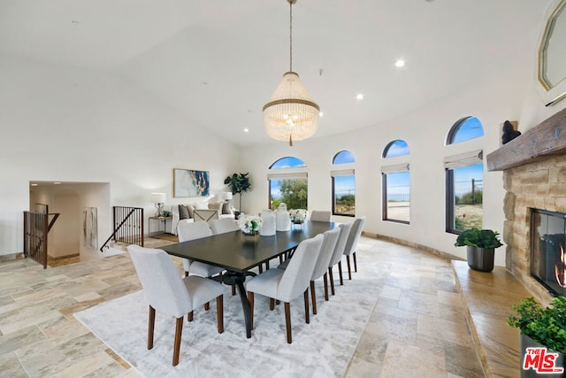 dining area featuring a fireplace, high vaulted ceiling, and a chandelier