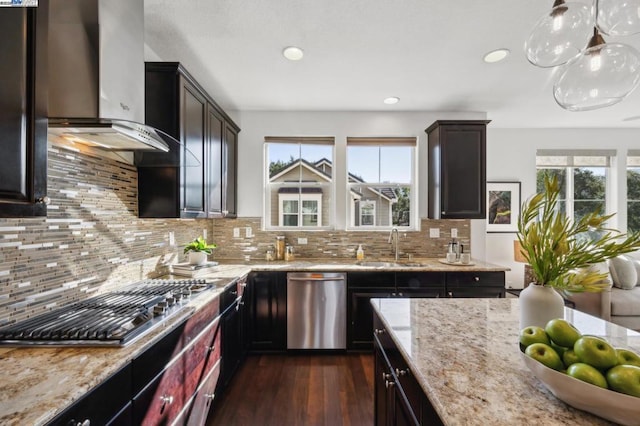 kitchen featuring dark wood-type flooring, wall chimney exhaust hood, sink, decorative light fixtures, and appliances with stainless steel finishes