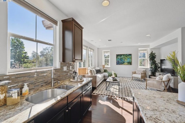 kitchen with dark hardwood / wood-style flooring, sink, backsplash, and light stone countertops