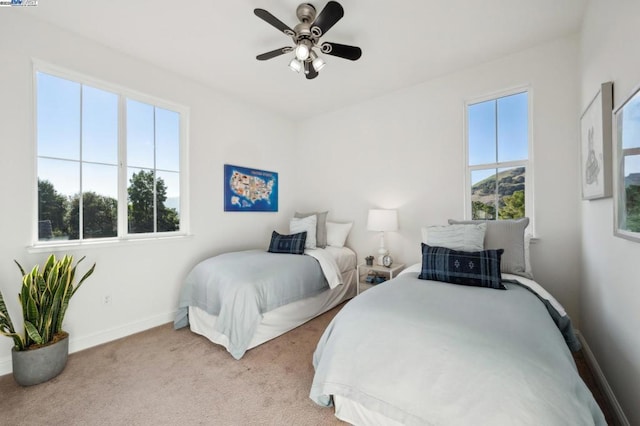 bedroom featuring ceiling fan, light colored carpet, and multiple windows