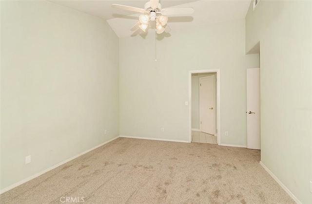 carpeted spare room with ceiling fan and high vaulted ceiling