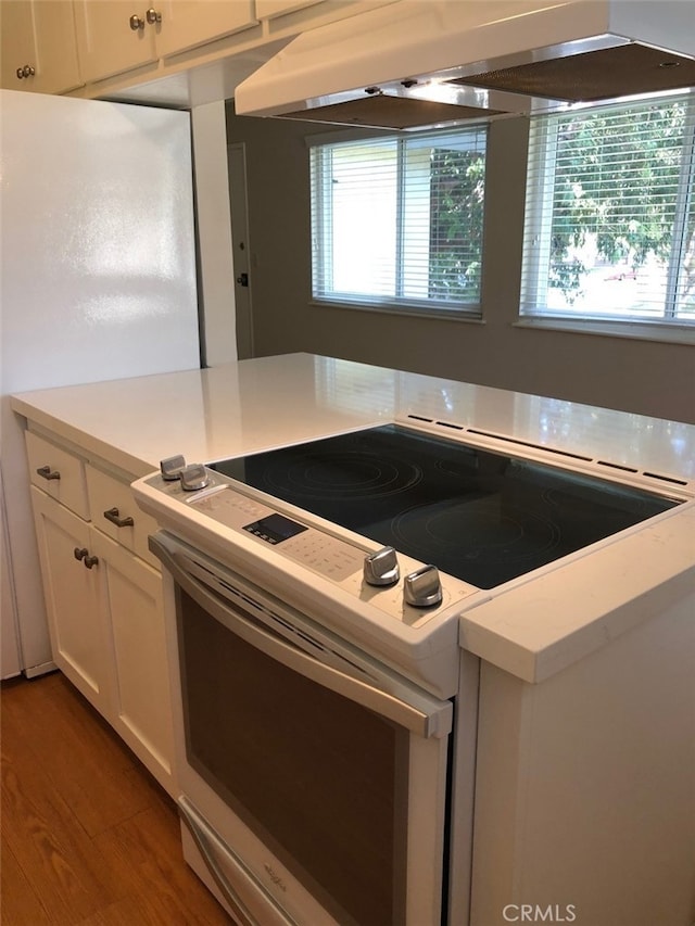 kitchen featuring white cabinetry, extractor fan, white appliances, and hardwood / wood-style floors