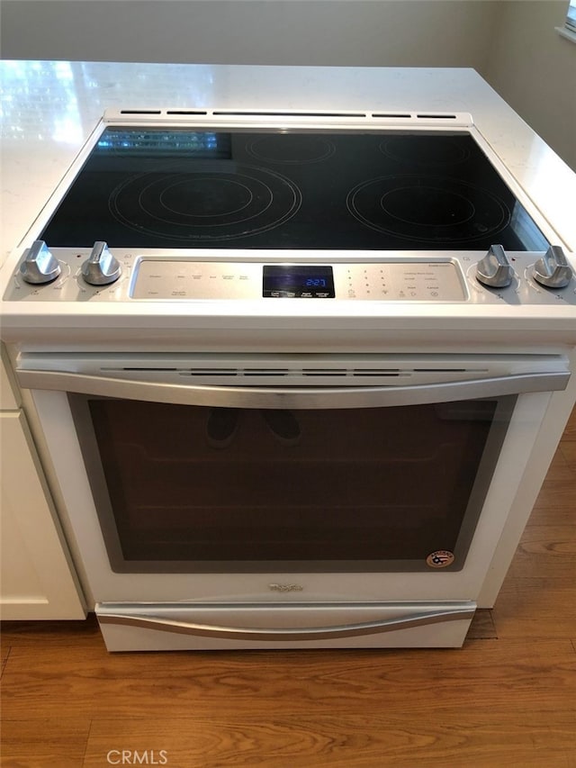 details with white cabinetry, range with electric cooktop, and wood-type flooring