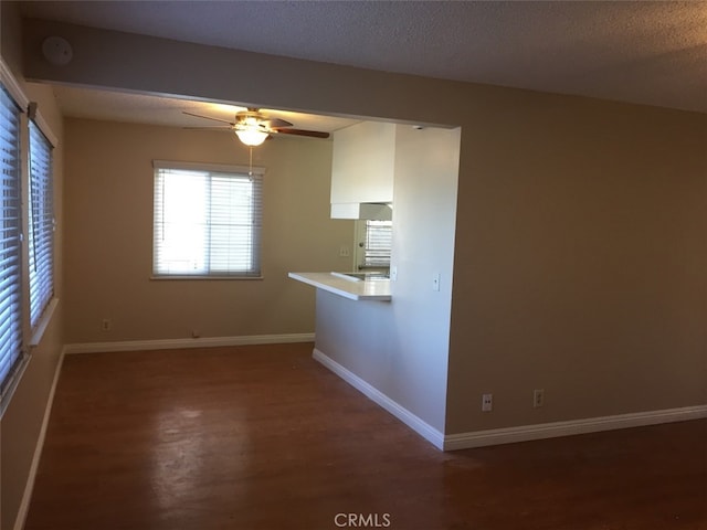 kitchen featuring dark hardwood / wood-style flooring, ceiling fan, kitchen peninsula, and a textured ceiling