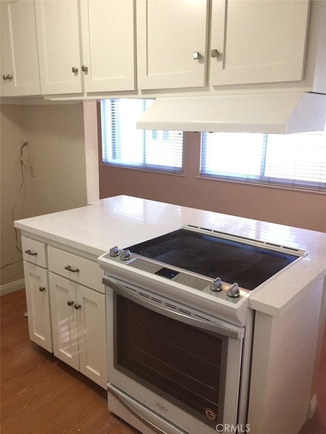 kitchen with electric stove, white cabinetry, exhaust hood, and dark hardwood / wood-style floors