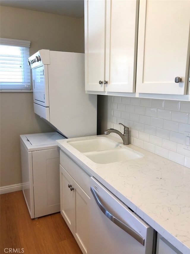 laundry room with cabinets, stacked washer and clothes dryer, sink, and hardwood / wood-style floors