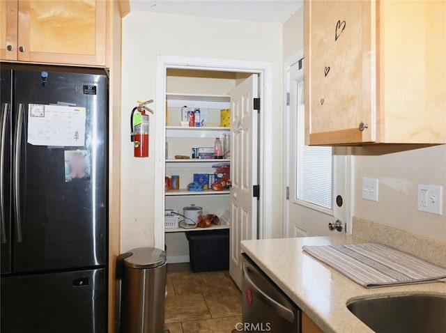 kitchen featuring tile patterned flooring, fridge, stainless steel dishwasher, and light brown cabinetry