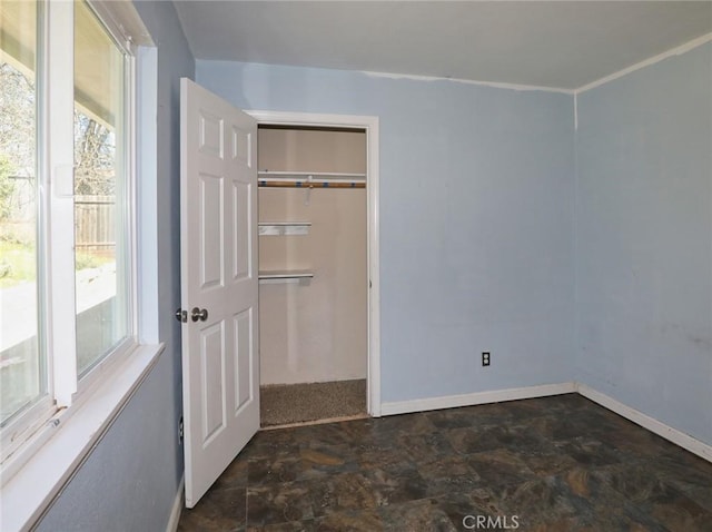 unfurnished bedroom featuring stone finish floor, baseboards, and a closet