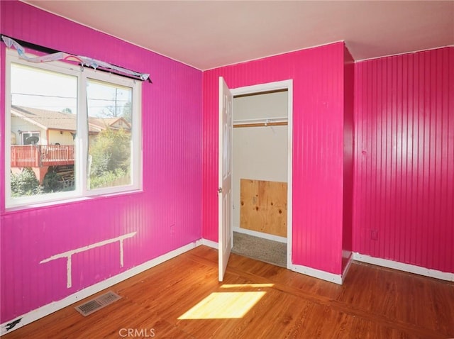 unfurnished bedroom featuring a closet, wood finished floors, visible vents, and baseboards