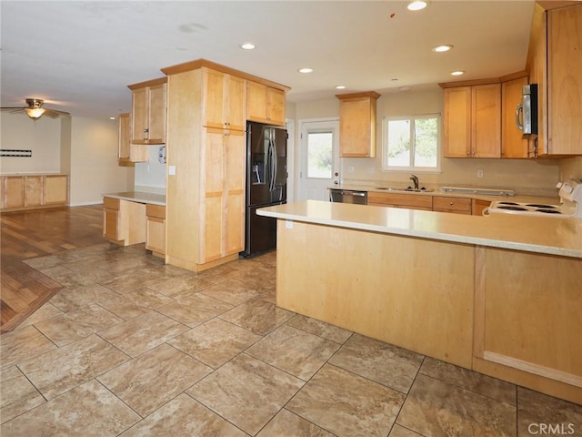 kitchen featuring stainless steel appliances, a sink, a peninsula, and light brown cabinetry