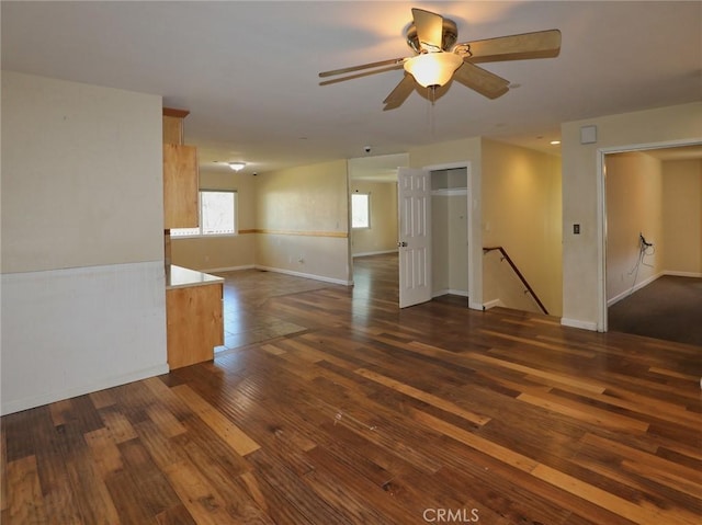 unfurnished room with a ceiling fan, dark wood finished floors, and baseboards