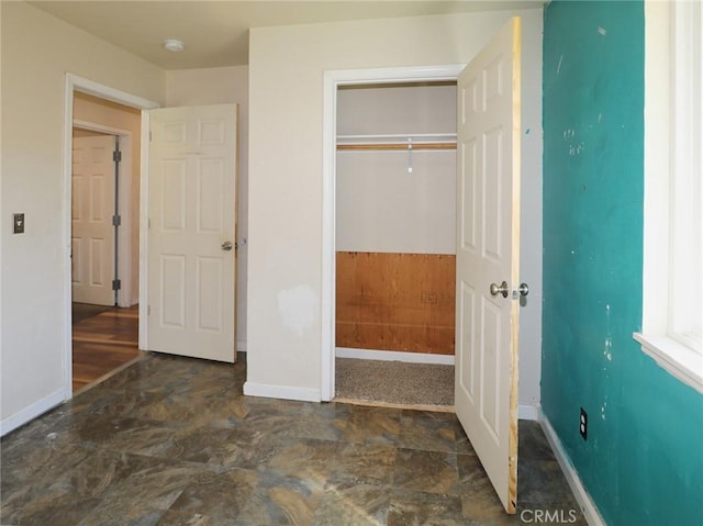 unfurnished bedroom featuring stone finish flooring, baseboards, and a closet