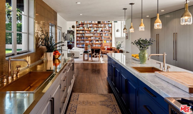 bar featuring dark hardwood / wood-style flooring, sink, pendant lighting, and blue cabinetry