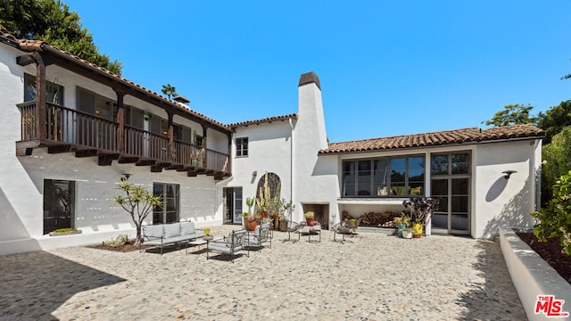 back of house featuring a balcony, outdoor lounge area, and a patio area