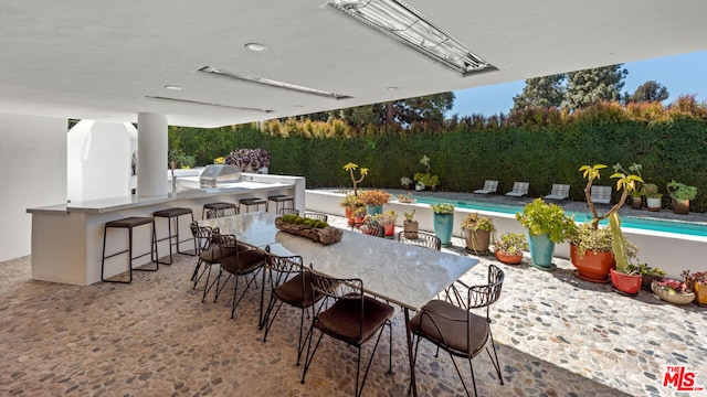 view of patio featuring a fenced in pool, exterior kitchen, and exterior bar