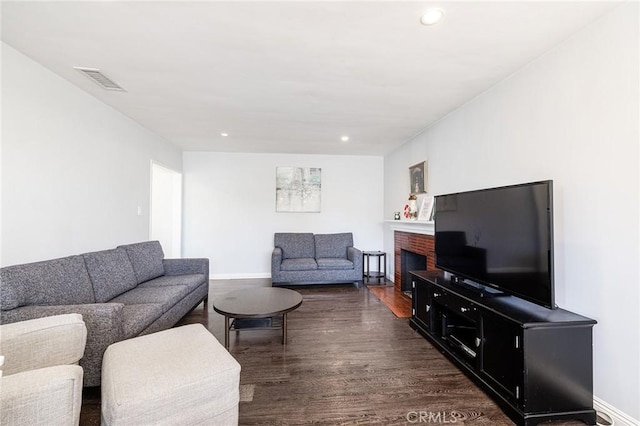 living room with dark wood-type flooring and a fireplace