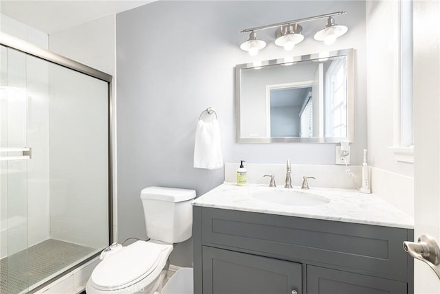 bathroom featuring vanity, a shower with shower door, and toilet