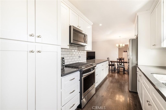 kitchen with decorative light fixtures, white cabinetry, backsplash, stainless steel appliances, and dark wood-type flooring