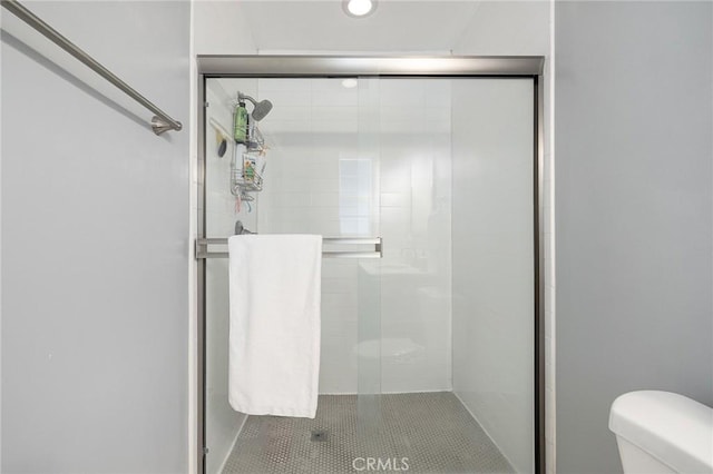 bathroom featuring an enclosed shower, tile patterned flooring, and toilet