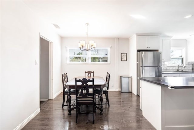 dining room featuring dark wood-type flooring, sink, and a notable chandelier