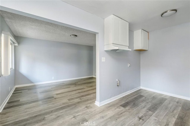 clothes washing area featuring light wood-type flooring, baseboards, and a textured ceiling