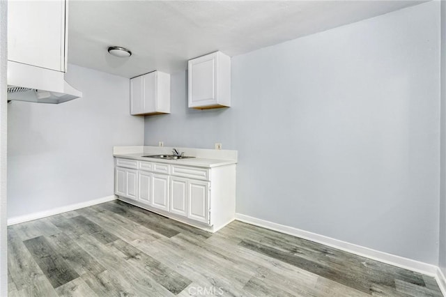 interior space featuring a sink, light wood-style flooring, and baseboards