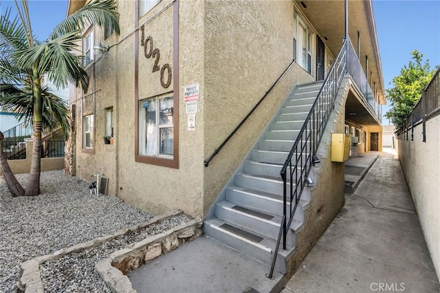 view of home's exterior with stairway and stucco siding