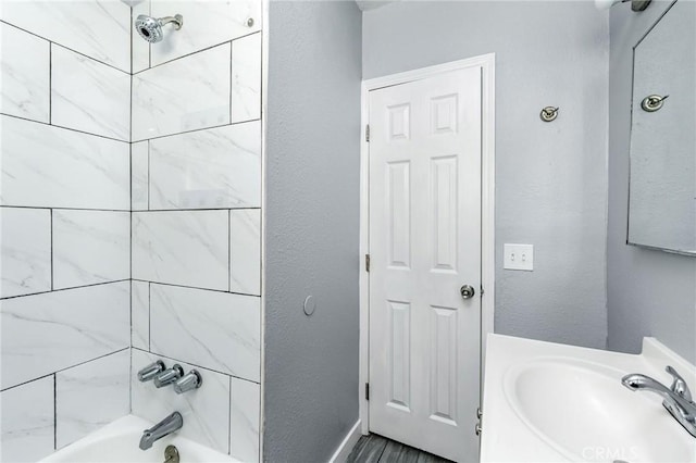 full bathroom featuring a textured wall, vanity, and shower / tub combination