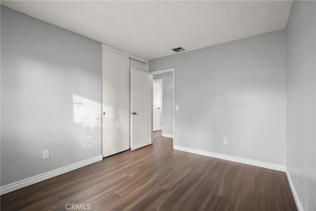 unfurnished room with dark hardwood / wood-style flooring and a textured ceiling