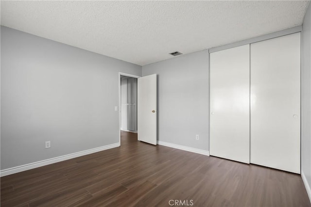 unfurnished bedroom featuring dark hardwood / wood-style floors, a closet, and a textured ceiling