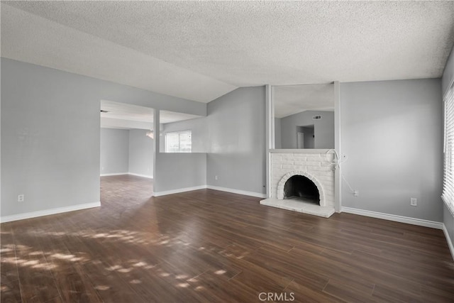 unfurnished living room with dark hardwood / wood-style floors, lofted ceiling, a fireplace, and a textured ceiling