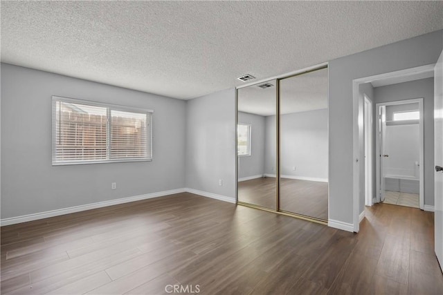 unfurnished bedroom with dark hardwood / wood-style floors, a closet, and a textured ceiling