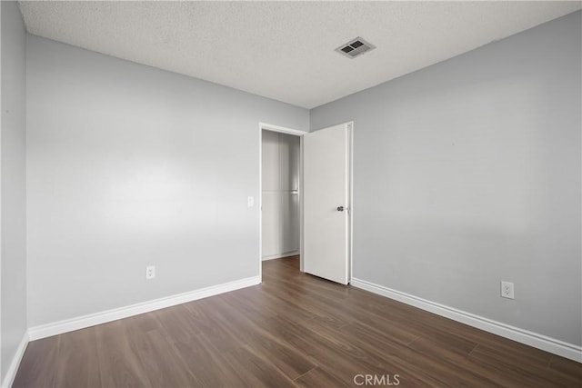 unfurnished room featuring dark wood-type flooring and a textured ceiling