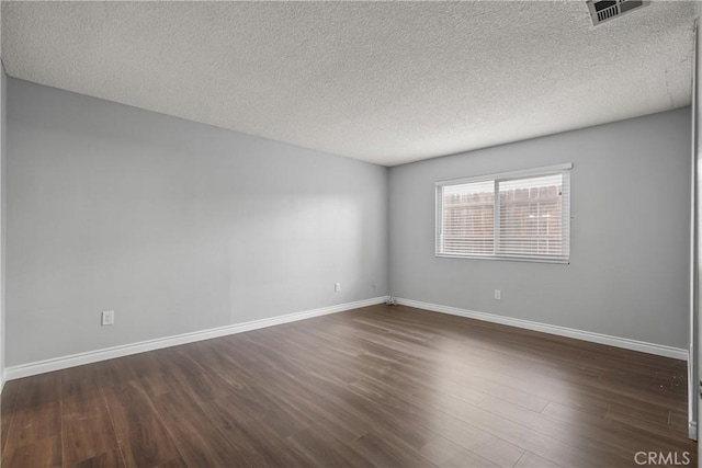 unfurnished room with dark wood-type flooring and a textured ceiling